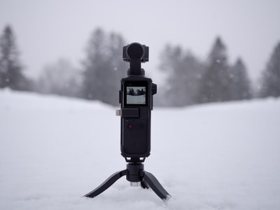 站在雪地上的黑色照相机